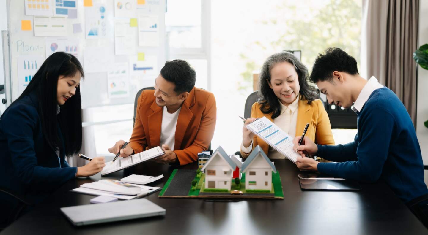 balancing the property sector The real estate agent is explaining the house style to see the house design and the purchase agreement.Wooden house at modern office