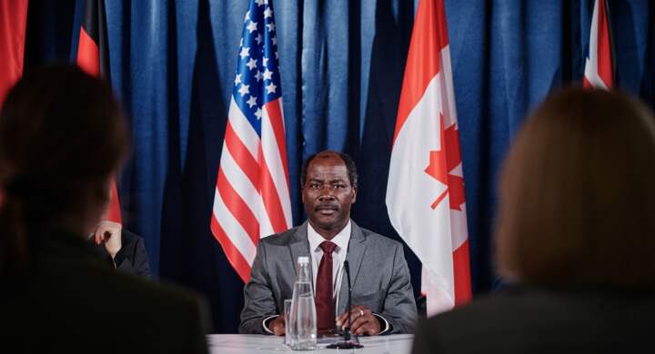 African American representative sitting at table and taking to journalists during press conference
