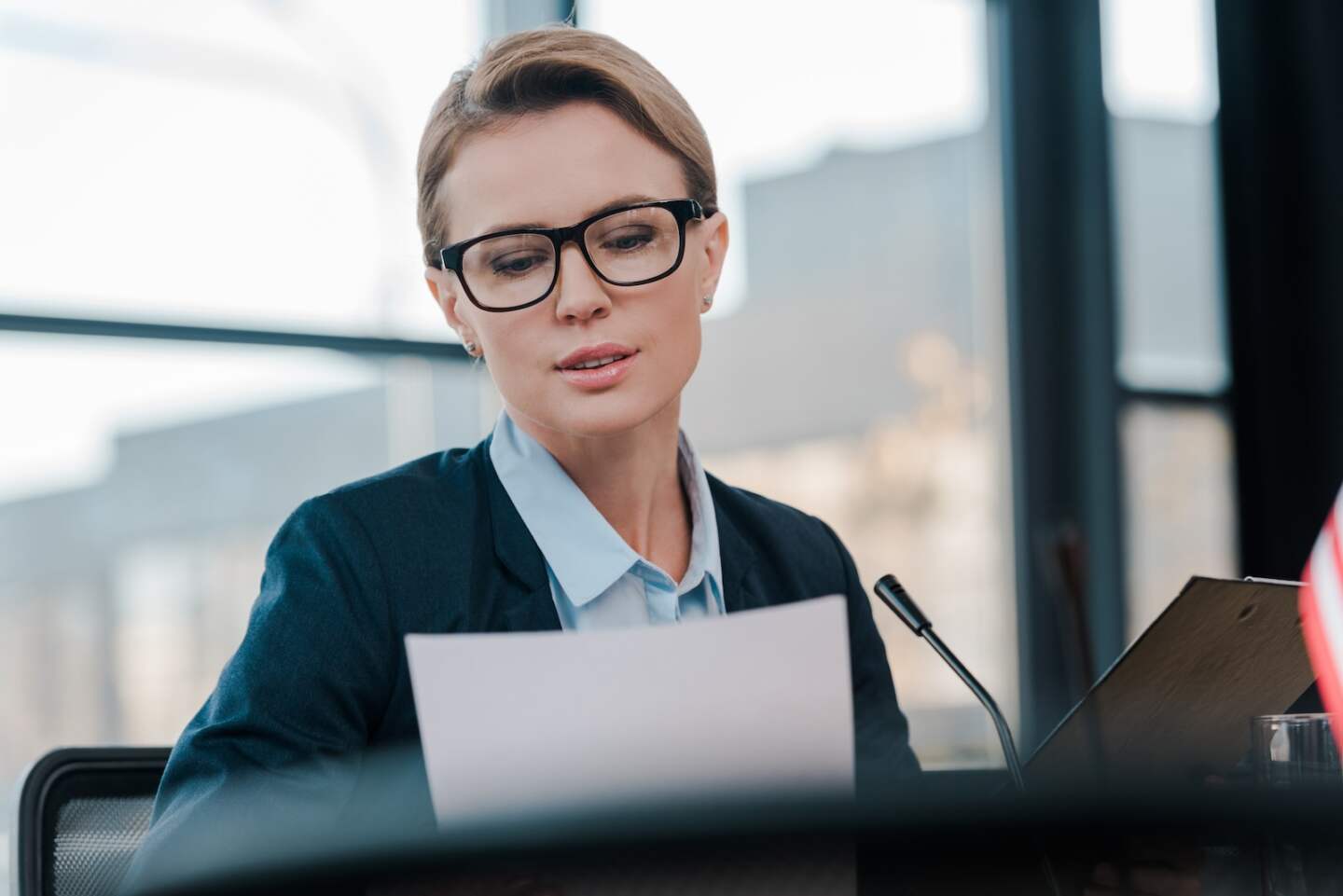 selective focus of attractive diplomat in eyeglasses looking at document