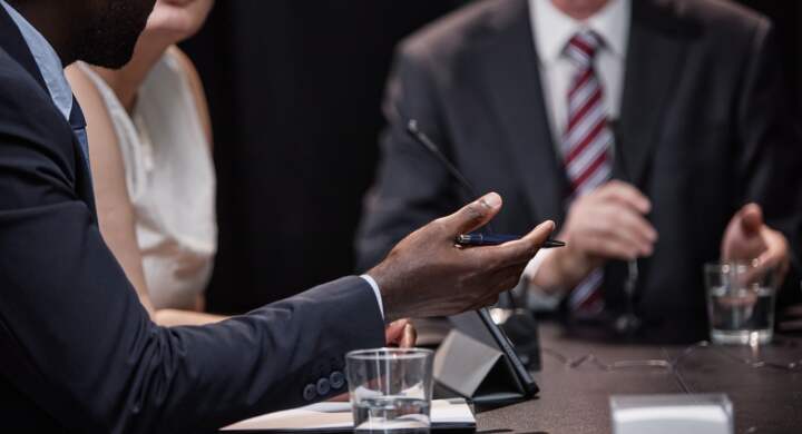 Cropped shot of African American politician negotiating with colleague chairing meeting asking man questions during political debate or press conference, copy space