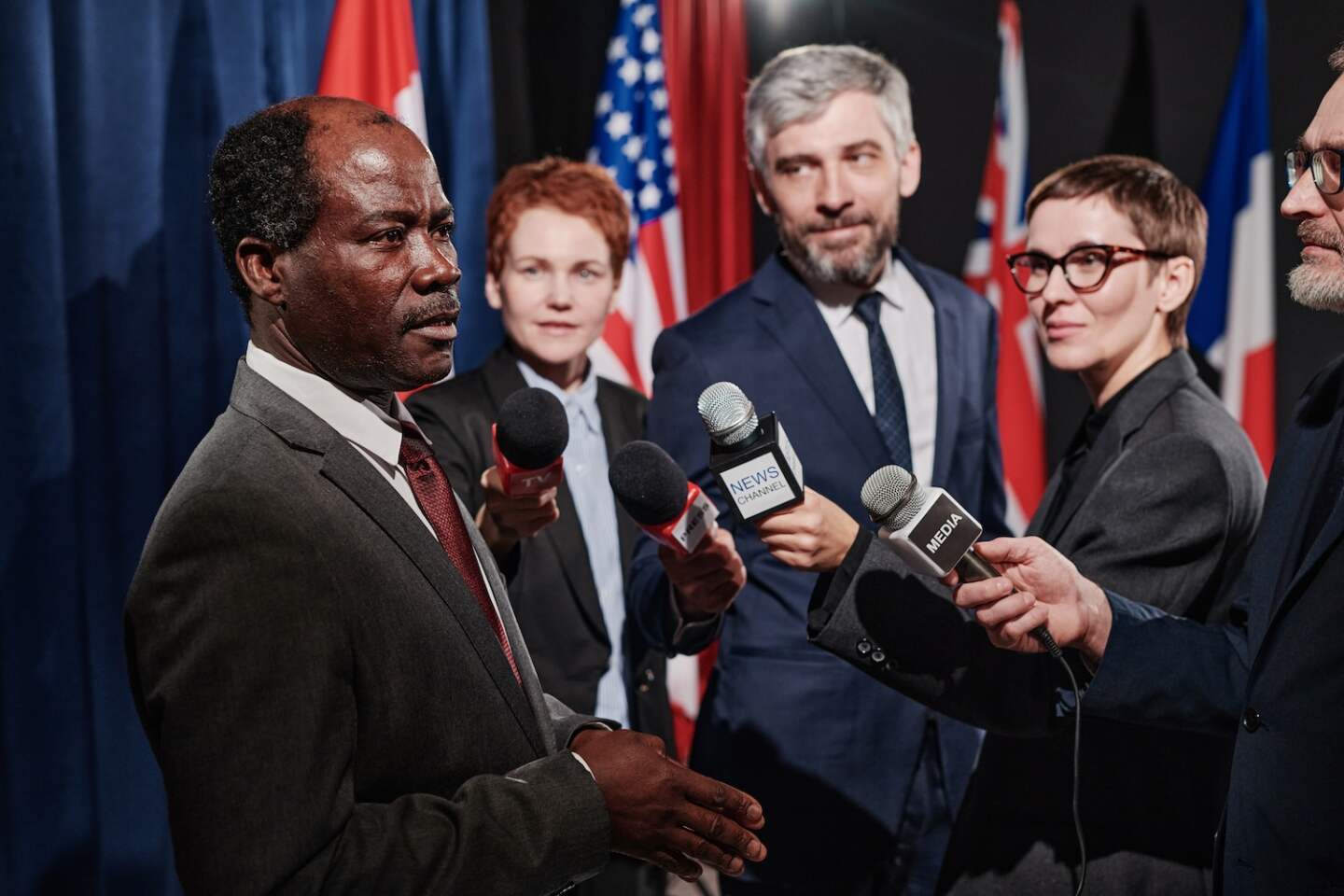 African mature politician giving an interview to journalists with microphones during press conference