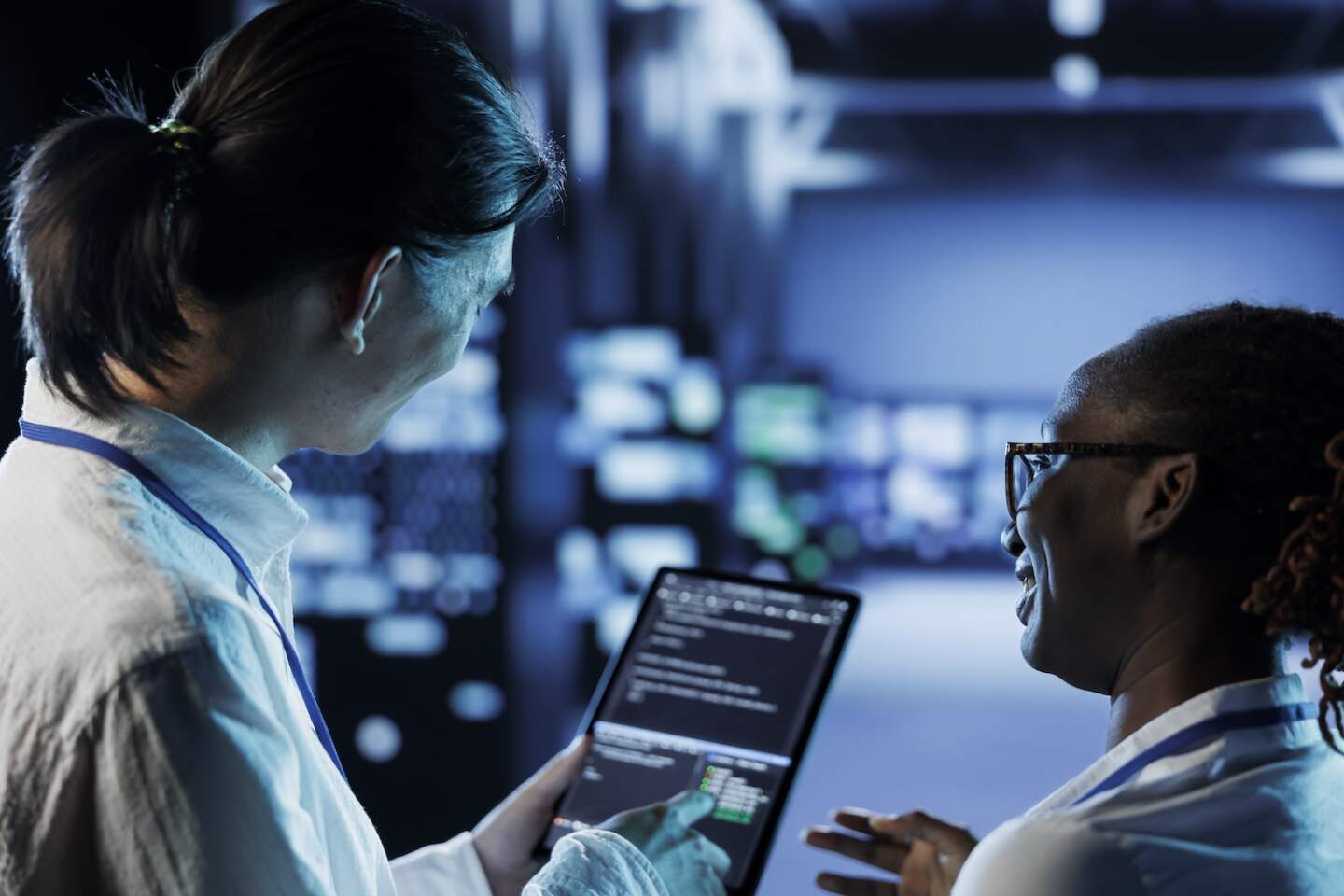 Engineer and african american colleague building firewall systems in server room. Man and woman running code on tablet to upgrade data center rigs handling demanding workloads