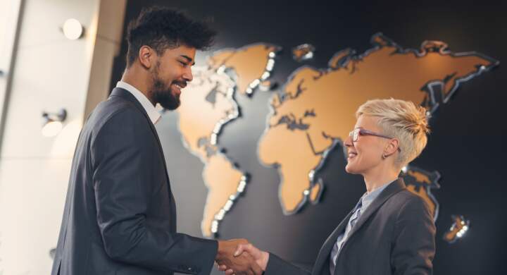Businessman and business woman shaking hands after achieving agreement and signing contract. Focus on the woman