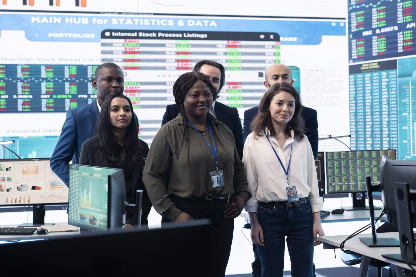 Diverse group of business professionals posing together in monitoring room, multinational company headquarters. Executive management team working with big data screen in the office.