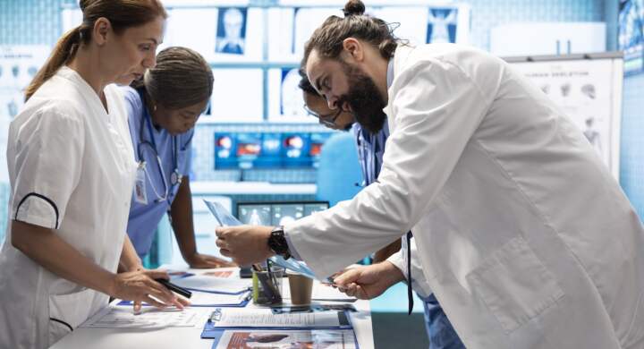 Medic discuss human anatomy scans in a radiology diagnostic meeting at a treatment center, teamwork and expertise in analyzing x ray results. Doctors examine hospital records and analytics.