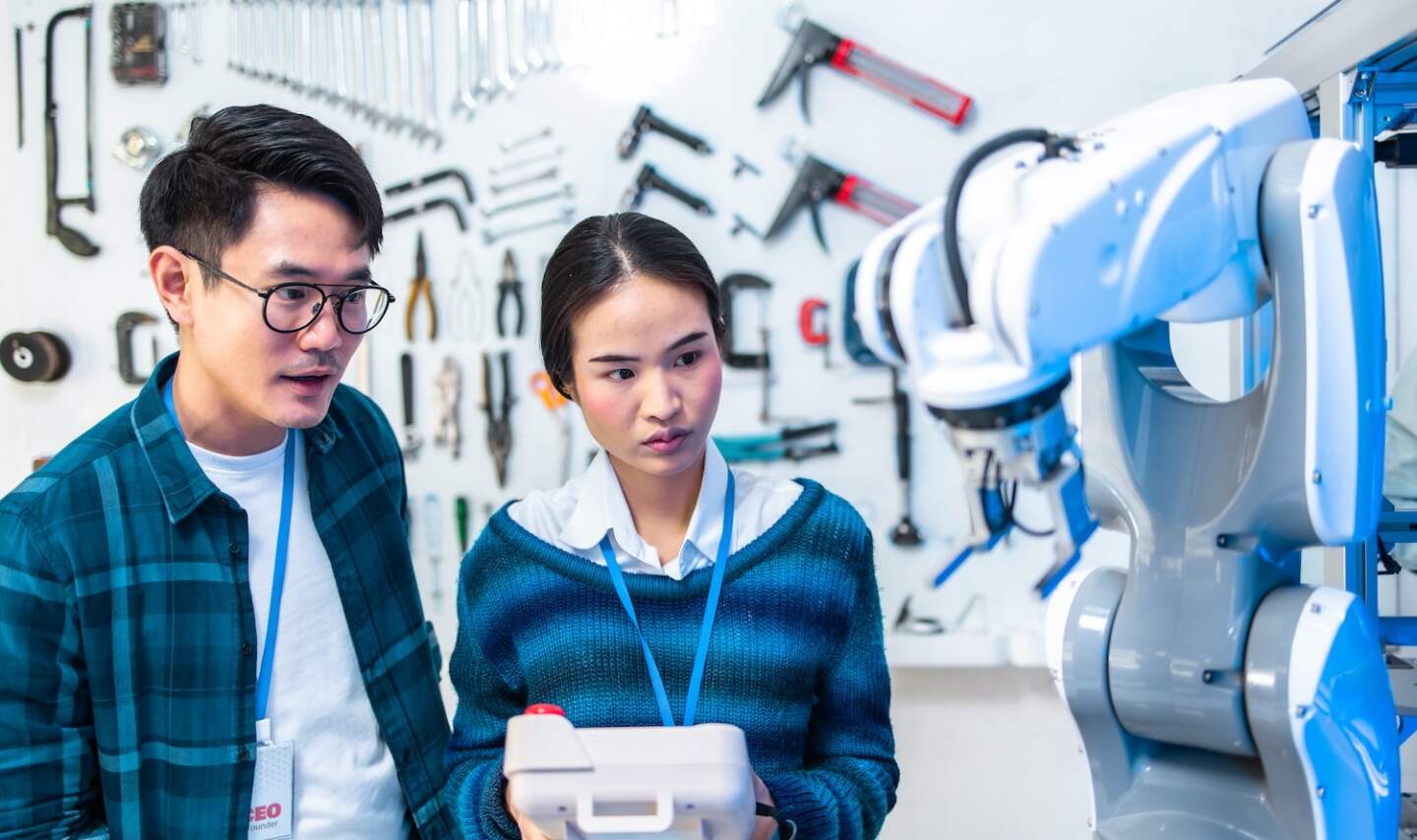 Caucasian and asian Engineers Maintenance Robot Arm at Lab. they are in a High Tech Research Laboratory with Modern Equipment. Professional Japanese Development Engineer Testing an Artificial Intelligent.