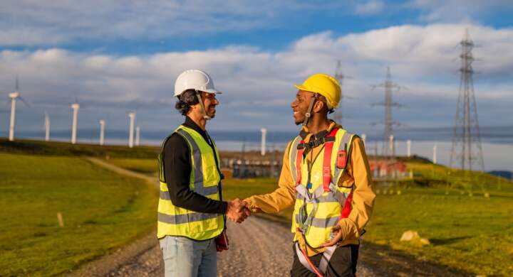 Engineers shaking hands at wind power station for renewable energy